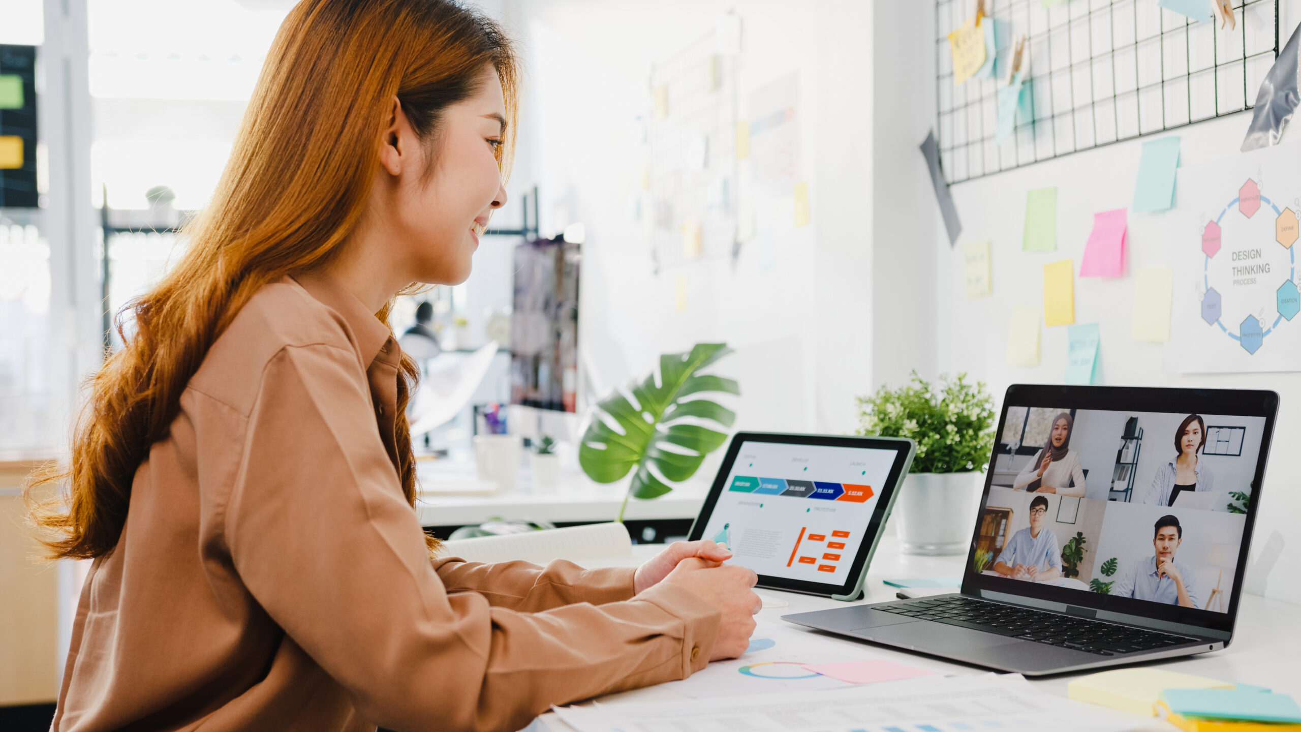 Asia businesspeople using laptop talk to colleagues discussing business brainstorm about plan in video call meeting in new normal office. Lifestyle social distancing and work after corona virus.